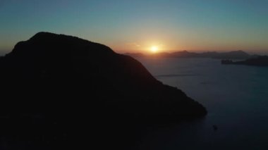 Gün batımında El Nido 'da tropikal havadan izleniyor. Sabahları dağları ve kayalık adaları olan deniz manzarası. Gün batımı gökyüzü ve körfez kayaları. Denizin üzerinde gün batımı
