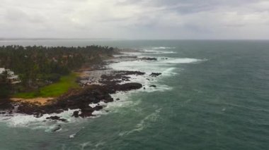 Rocky coastline with beaches and ocean waves rolling ashore. Matara, Sri Lanka.