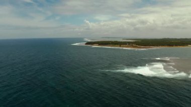 Tropik adanın kıyıları, gökyüzüne ve mavi sulara karşı orman ve palmiye ağaçlarıyla kaplı bir deniz burnu. Siargao, Filipinler