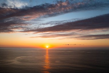 Beautiful sunset background from the colorful beams on the sky. Sunrise over ocean. Seascape.