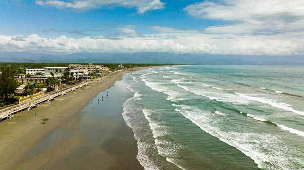 Aerial view of coast with hotels and tourists, a famous place for surfing in the Philippines. Sabang Beach, Baler, Aurora, Philippines.