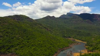 Aerial view of lake among mountains covered rainforest and blue sky with clouds. Kalu Ganga Reservoir, Sri Lanka.