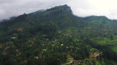 Aerial view of village among mountain hills with tea plantations and agricultural lands. Ramboda, Sri Lanka.