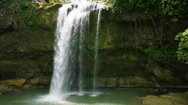 A beautiful waterfall among the rainforest and vegetation. Slow motion. Ben-Ben Falls in mountain jungle. Negros, Philippines.