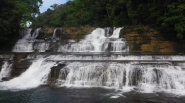 Yeşil bitki örtüsüyle çevrili tropikal bir ormandaki hava manzaralı orman şelalesi. Dağ ormanında Tinuy-an Şelalesi. Filipinler, Mindanao.