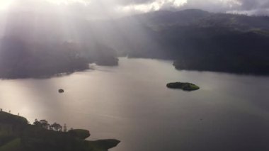 Gölün yüzeyindeki güneş ışınlarının hava aracı dağlık bir bölgedeki tepelerin çevresindeydi. Maskeliya, Sri Lanka.