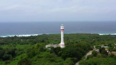 Büyük bir adada beyaz kule deniz feneri, hava manzaralı. Yağmur ormanı tepesi ve deniz feneri kulesi. Bolinao Deniz Feneri, Luzon, Filipinler. Yaz ve seyahat tatil konsepti.