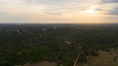 Sri Lanka milli parkındaki dağların arka planında, ormanın üzerinde gün batımının hava manzarası.