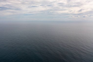 Dalgalı mavi deniz manzarası ve bulutlu gökyüzü. Okyanus silüeti.