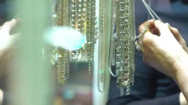 Kadınlar satın almak için gümüş zincirli kolye seçer. Mağazada bijouterie seçen kadınlar.