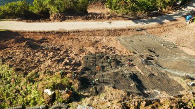 İşçiler dağın yamacını metal ağlarla güçlendirerek kayaların düşmesini ve toprak kaymasını önlüyor. Heyelan önleyici beton duvar inşa eden işçiler kayalara karşı koruma sağladılar