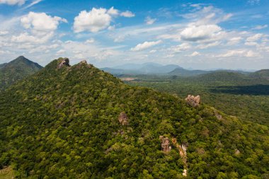 Yeşil ormanlarla kaplı dağların tepesi ve mavi gökyüzüne ve bulutlara karşı ormanı olan bir vadi. Sri Lanka.