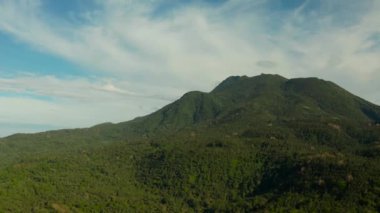 Dağlar yağmur ormanları, ağaçlar ve bulutlu mavi gökyüzü, hava manzarası. Camiguin, Filipinler. Tropikal adada dağ zirveleri ormanla kaplı bir dağ manzarası. Dağların yamaçları
