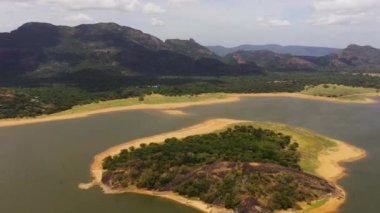 Tropikal manzara: dağların arka planına karşı bir ormanın ortasında bir göl. Sri Lanka 'daki Kandalama Barajı.