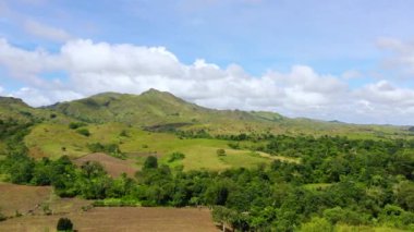 Yeşil çimenli tepeler ve beyaz kabarık bulutlu mavi gökyüzü. Luzon adasının güzel manzarası, hava manzarası.