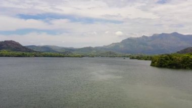 Ormanla kaplı dağların arasındaki göl manzarası. Sri Lanka 'daki Loggal Oya Barajı.