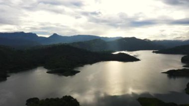Sabahın erken saatlerinde yeşil tepeler ve dağların arasındaki göl manzarası. Tropik bir manzara. Victoria Barajı, Sri Lanka.