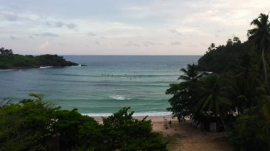 Gün batımında körfezde sörfçülerin hava aracı. Hiriketiya, Sri Lanka.