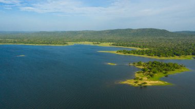 Dağların arka planında tropikal orman ve ormanlarla dolu bir göl. Kantale tankı, Sri Lanka.