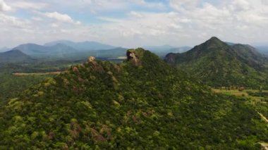 Yeşil ormanlarla kaplı dağların ve mavi gökyüzüne ve bulutlara karşı ormanın havadan görünüşü. Sri Lanka.