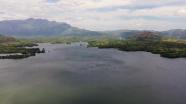 Aerial view of lake with islands surrounded by mountains with a tropical forest. Loggal Oya Reservoir. Sri Lanka.