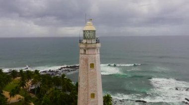 Deniz feneri ve büyük dalgalar ve sörflerle dolu mavi okyanus. Dondra, Matara, Sri Lanka.