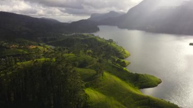 Dağların arasındaki güneş ışığı gölü ve çay tarlaları olan yeşil tepeler. Maskeliya, Maussakelle rezervi, Sri Lanka.