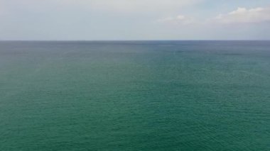 Sakin denizin üzerinde mavi gökyüzünde güzel beyaz bulutlar. Sakin su yüzeyinin sakin deniz uyumu.