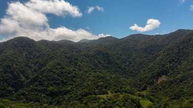 Aerial view of Mountains covered rainforest, trees and blue sky with clouds. Philippines.