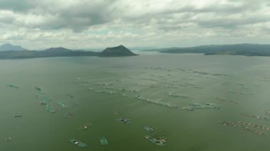 Taal Gölü üzerinde bir volkan ve balık çiftliği manzaralı kafesler var. Luzon, Filipinler Tropikal manzara, dağlar ve göldeki volkan.