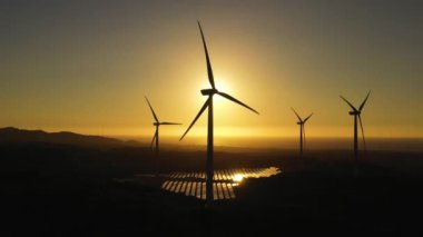 Günbatımında deniz kıyısında rüzgar türbinleri olan Rüzgâr Çiftliği 'nin en üst görüntüsü. Rüzgar santrali. Filipinler.