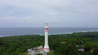 Deniz kenarındaki bir tepede deniz feneri. Okyanus kıyısında yağmur ormanları ve deniz feneri var. Tropikal bir adada deniz feneri, üst manzara. Cape Bolinao Deniz Feneri, Luzon, Filipinler. Yaz ve seyahat tatili