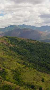 Aerial view of Mountains covered rainforest, trees and blue sky with clouds. Philippines.