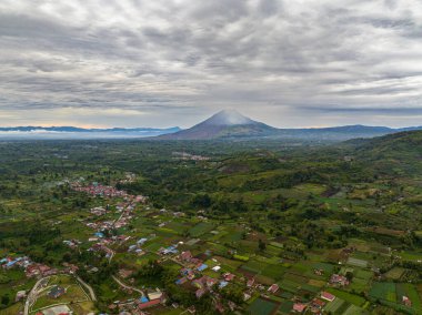 Gün batımında Berastagi ve Sinabung yanardağlarının hava manzarası. Sumatra, Endonezya.