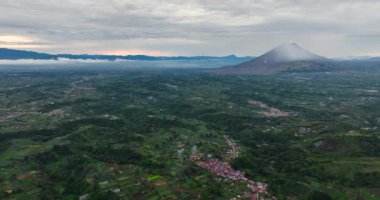 Çiftlik arazisi ve Sinabung volkanı gün batımında. Berastagi şehri. Sumatra, Endonezya.