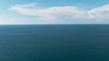Dalgalı mavi okyanus ve yukarıdan bulutlu gökyüzü. Gökyüzüne karşı dalgalı mavi deniz suyu.