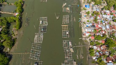 Nehirde kafesleri ve ağları olan balık çiftliğinin en iyi manzarası. Balıkçı köyü Hinigaran Nehri. Zenciler, Filipinler