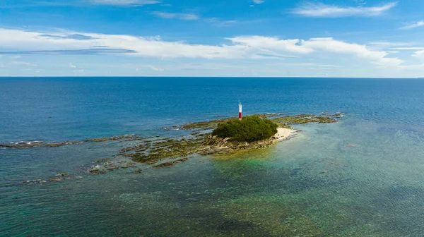 Mavi denizde deniz feneri olan kayalık adanın havadan görünüşü. Borneo, Malezya.