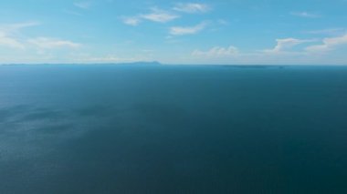 Gökyüzüne ve bulutlara karşı açık mavi okyanus. Denizin üzerinden uçmak. Tropik bölgelerde deniz manzarası. Borneo, Malezya.