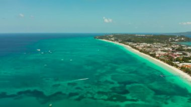 Mavi deniz kıyısında turistlerin ve otellerin olduğu tropik beyaz plaj, hava manzaralı. Yaz ve seyahat tatil konsepti.