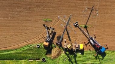 İşçilerin hava görüntüsü inşaat ekipmanı ve vinç kullanarak yüksek voltaj hattı desteği kuruyor. Güç hattı destek kurulumu.