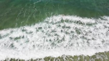 Drone 'dan deniz dalgaları görüntüsü. Sahilde okyanus dalgaları. Kumsal ve dalgalar, yukarıdan. Yaz ve seyahat tatili konsepti. Mavi deniz ve kumlu sahil.