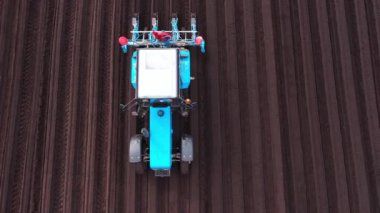 Tractor sowing seeds with a seeder driller in a field. Top view of tractor sowing and cultivating field.