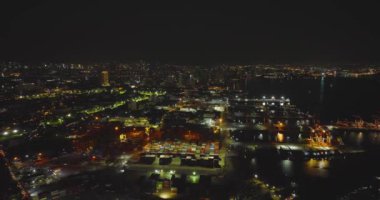 Manila şehrinin aydınlık gökdelenleri ve geceleri liman manzarası.