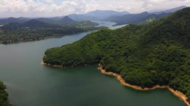 Yeşil orman ve ormanla kaplı dağların arasındaki göl manzarası. Victoria Barajı, Sri Lanka.