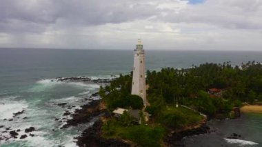Büyük dalgalar ve sörflerle deniz feneri ve mavi okyanus manzarası. Dondra, Matara, Sri Lanka.