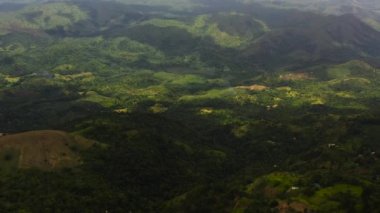 Yukarıdan ormanla kaplı dağ zirveleri. Dağlar yağmur ormanlarıyla, ağaçlar ve bulutlarla kaplı mavi gökyüzü. Sri Lanka.