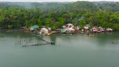 Balıkçı köyü, tekneleri, gecekondu mahalleleri, ahşap evleri, insansız hava aracı. Balıkçı köyünde suyun içinde duran ev halkı. Luzon, Filipinler.