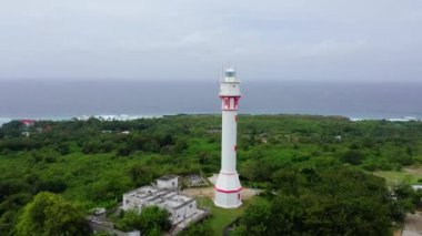 Büyük bir adada beyaz kule deniz feneri, hava manzaralı. Yağmur ormanı tepesi ve deniz feneri kulesi. Bolinao Deniz Feneri, Luzon, Filipinler. Yaz ve seyahat tatil konsepti.