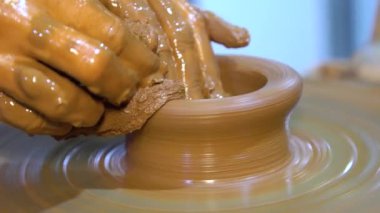 Tekerlek üzerinde çömlek yapan ellerin yakın çekimi. Çömlekçi çarklı çömlek atölyesi.